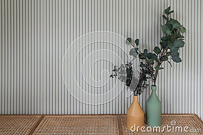 Working corner decorated with mustard color and green ceramic vase with artificial plant inside on natural rattan bench in natural Stock Photo
