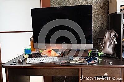 Working desk with computer and stuff.View over untidy workplace with modern computer, keyboard, earphones, leather Stock Photo