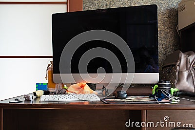 Working desk with computer and stuff.View over untidy workplace with modern computer, keyboard, earphones, leather Stock Photo