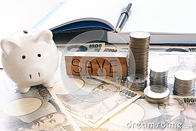 Working desk with yen and coins with note book, income and expense. Saving money concept Stock Photo