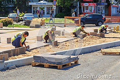 Working guest workers laying paving slabs in the city on the streets of the Young Guard in Sunny Summer Day Editorial Stock Photo