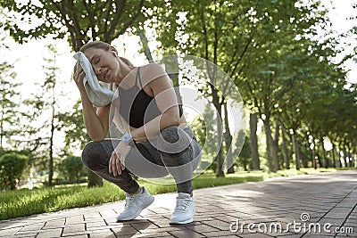 Working hard. Tired fitness woman in sportswear feeling exhausted after active morning workout in the city park. Sport Stock Photo