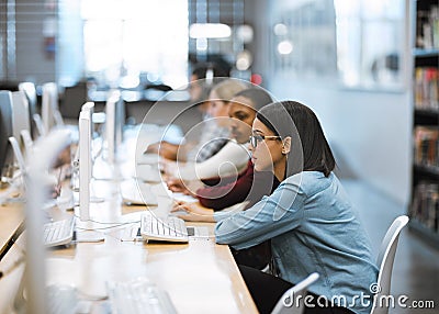 Working hard to complete all their assignments. Shot of a group of university students working on computers in the Stock Photo