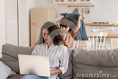 Work from home with naughty kid: young mom use laptop for business sit on sofa with bored son attack Stock Photo
