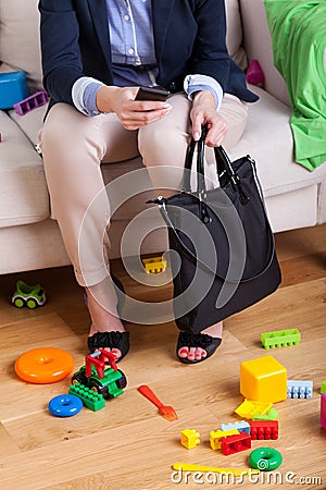 Working lady sitting on couch surrounded by clothes and toys Stock Photo