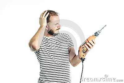 A working man in perplexity pondered look at a power tool - electric drill. Isolated on white Stock Photo