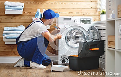 Working man plumber repairs washing machine in laundry Stock Photo