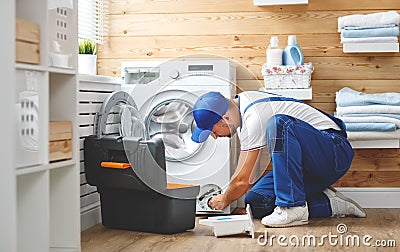 Working man plumber repairs washing machine in laundry Stock Photo