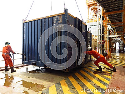 Working men taking off external load with lifting crane. Two constructors loading or discharging cargo. Workers remove cargo with Editorial Stock Photo
