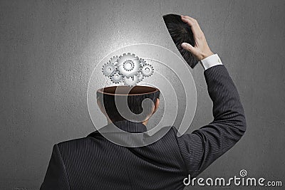 Working metal gears inside businessman head in gray concrete wall background Stock Photo