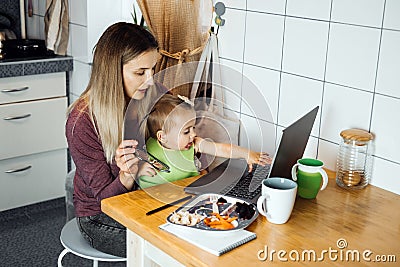 Working mother work remotely. Remote Work from home. Young mother with toddler baby girl working at home using laptop on Stock Photo