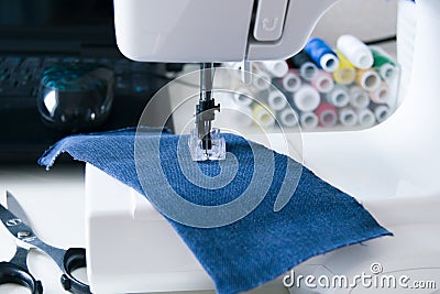 working part of a home sewing machine for handicrafts. Focus on sewing needle and piece of fabric, background selective focus on Stock Photo