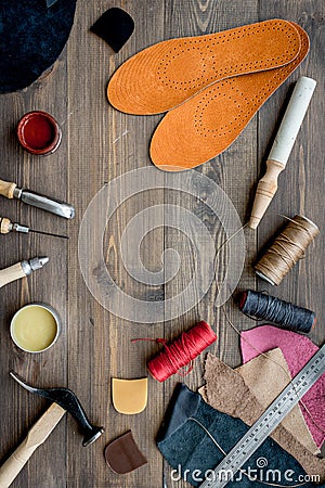 Working place of shoemaker. Skin and tools on brown wooden desk background top view copypace Stock Photo