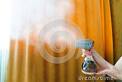 Working portable hand steamer for clothes in women's hands. Stock Photo