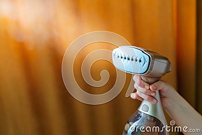 Working portable hand steamer for clothes in women's hands. Stock Photo