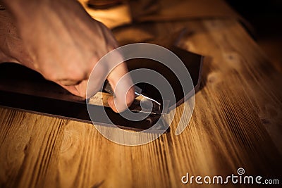 Working process of the leather belt in the leather workshop. Man holding crafting tool and working. Tanner in old Stock Photo