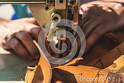 Working process of leather craftsman. Tanner or skinner sews leather on a special sewing machine, close up Stock Photo