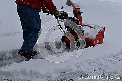 Snow blowing a driveway on a blustery winter day Editorial Stock Photo