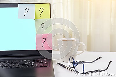 The working table of the freelancer. Stickers with question marks stick to the laptop. Stock Photo
