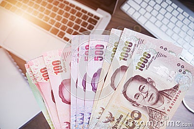 Thai money banknotes And laptop computer Work and money Stock Photo