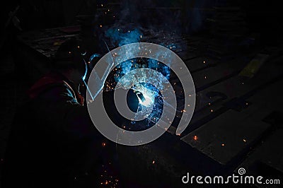 The working welder performs welding work in production using electric arc metal welding Stock Photo