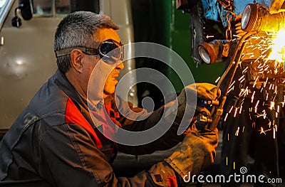 The working welder performs welding work in production using electric arc metal welding. Editorial Stock Photo