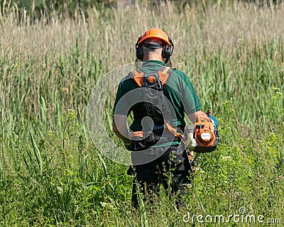 Workman clearing long grass and weeds Editorial Stock Photo