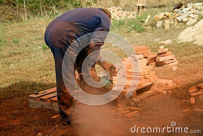 Workman cutting orange bricks with a radial saw Editorial Stock Photo