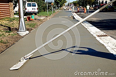 Workman finishes and smooths concrete surface on new sidewalk Stock Photo