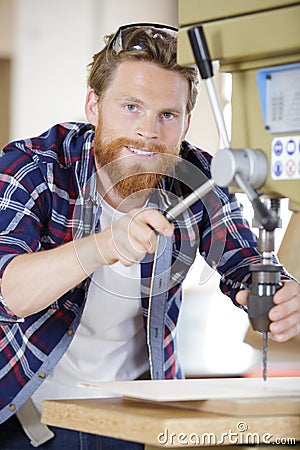 Workman lowering drill bit on machine Stock Photo