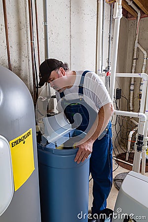 Workman replacing an old domestic water softener Stock Photo