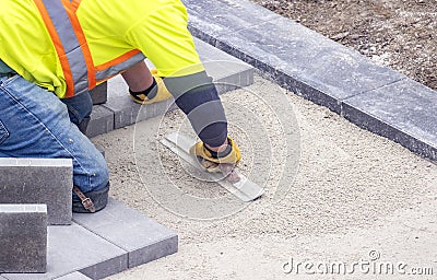 Workman in safety jacket preparing the foundation of patio pavers Stock Photo