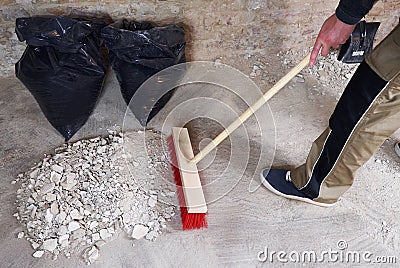 Workman sweeping the rubble with broom Stock Photo