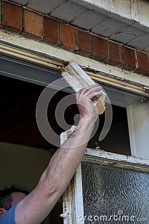 Workman using his hand and arm to remove old wooden window frame Stock Photo