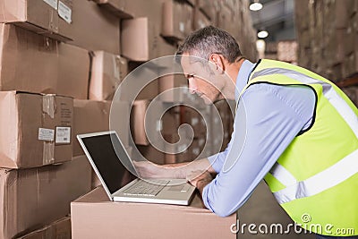 Workman using laptop at warehouse Stock Photo