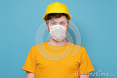 Workman wearing a yellow hard hat and medical mask during quarantine Stock Photo