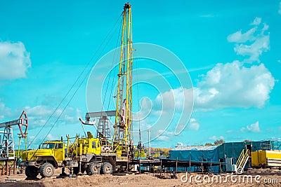 Workover rig working on a previously drilled well trying to restore production through repair. The pumping units and well workover Stock Photo