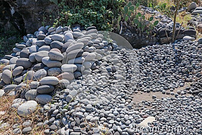 Workplace of Balinese stone gatherers. Sorted boulders by size. Natural building material. Hard work. Stones thrown from the sea a Stock Photo