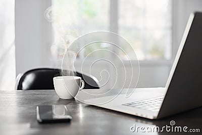 Workplace at home, laptop computer, mobile phone and coffee cup in morning. Business, technology, freelance, place of work concept Stock Photo
