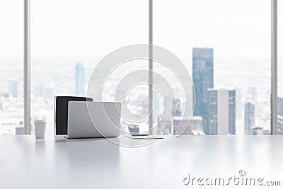 A workplace in a modern panoramic office in Manhattan, New York City. A laptop, notepad and a coffee cup are on the white table. Stock Photo