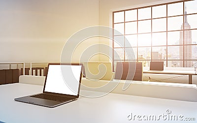 Workplaces in a bright modern loft open space office. Tables equipped with laptops, white copy space in the screen. Docs shelves. Stock Photo