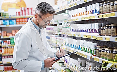 He works wonders when it comes to your wellness. a mature pharmacist doing inventory in a pharmacy. Stock Photo