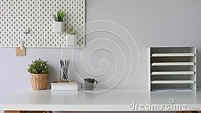 Workspace coffee cup that surrounded by document shelf, picture frame, pencils in glass vase, pine cone and notebooks. Stock Photo