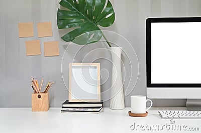 Workspace with computer, coffee mug, pencil and photo frame with sticky note on the wall Stock Photo