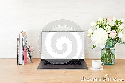 Workspace with laptop computer with blank white screen, feminine office supplies, flowers, books, stationery, coffee cup on wooden Stock Photo