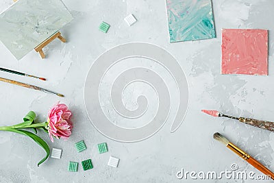 Workspace with palette knife, canvas painting, tulip flower and mosaic on gray backround Stock Photo