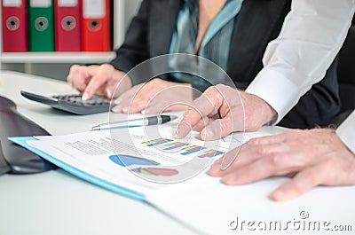 Workteam analyzing graphs and using a calculator Stock Photo