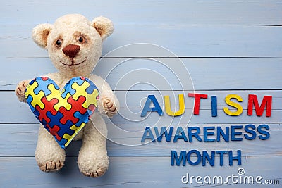 World Autism Awareness month, mental health care concept with teddy bear holding puzzle or jigsaw pattern on heart Stock Photo