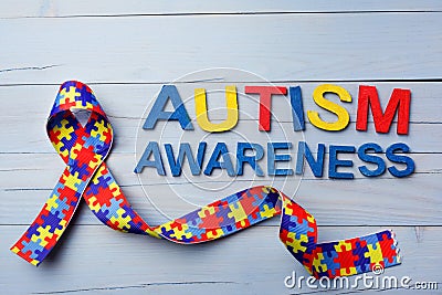 World Autism awareness and pride day or month with Puzzle pattern ribbon on blue wooden background. Stock Photo