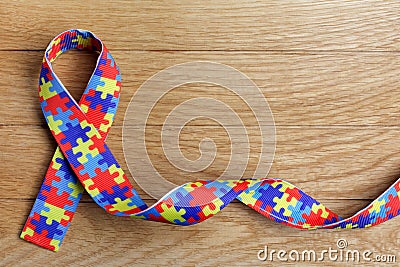 World Autism awareness and pride day or month with Puzzle pattern ribbon on wooden background. Stock Photo